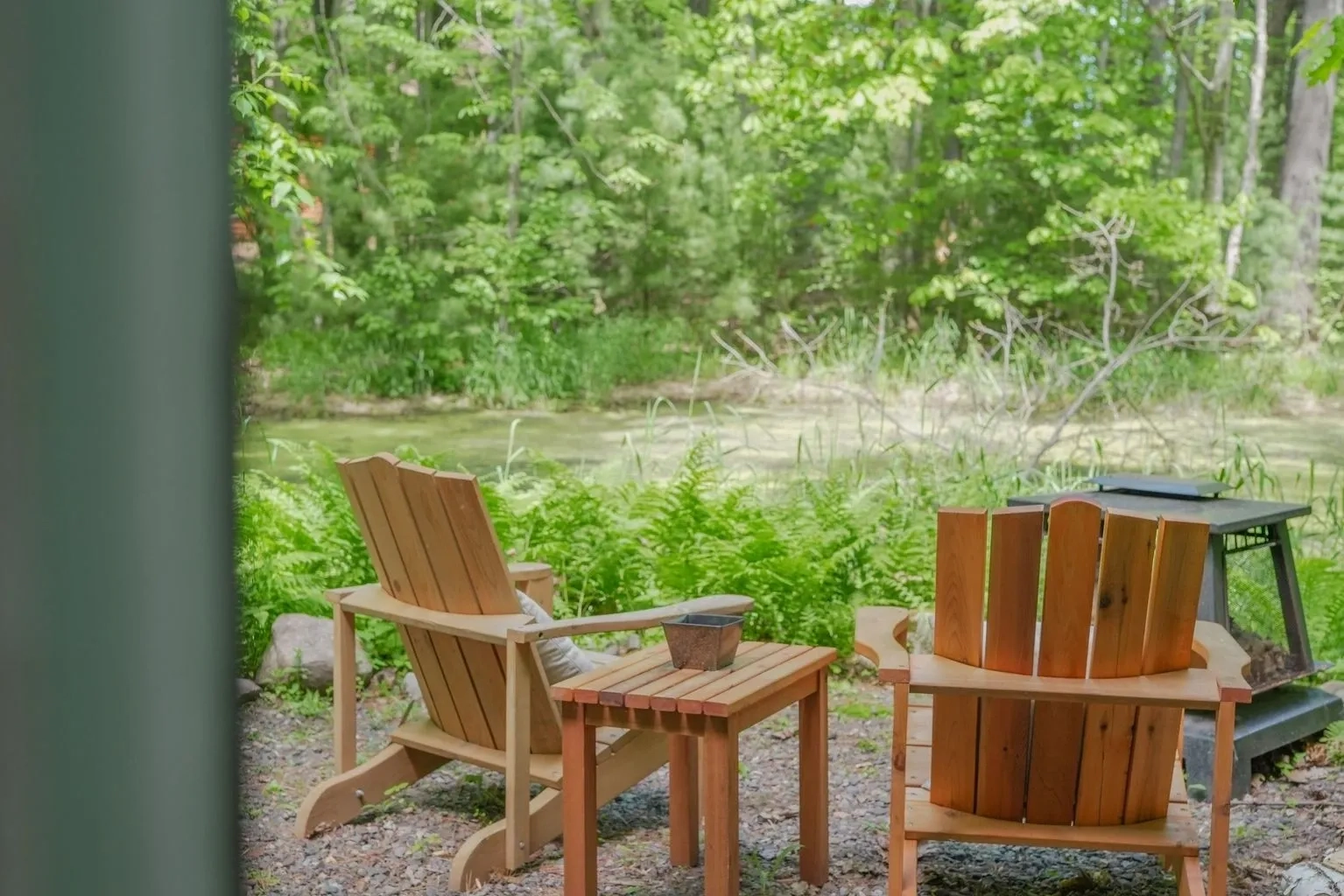 A couple of chairs and a table in front of some water.