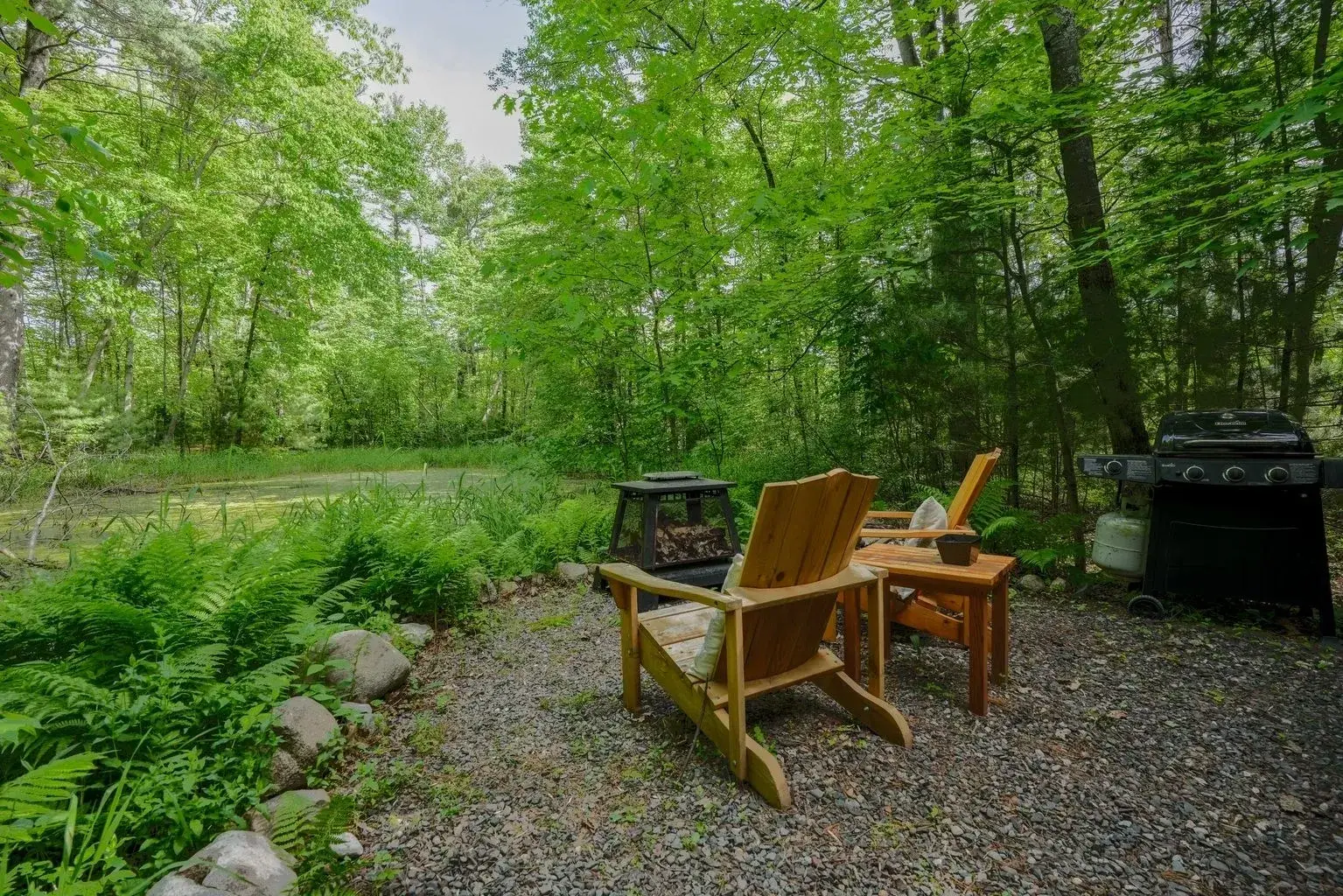 A couple of chairs and tables in the middle of a forest.