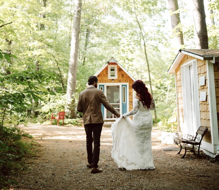 A man and woman walking in the woods holding hands.