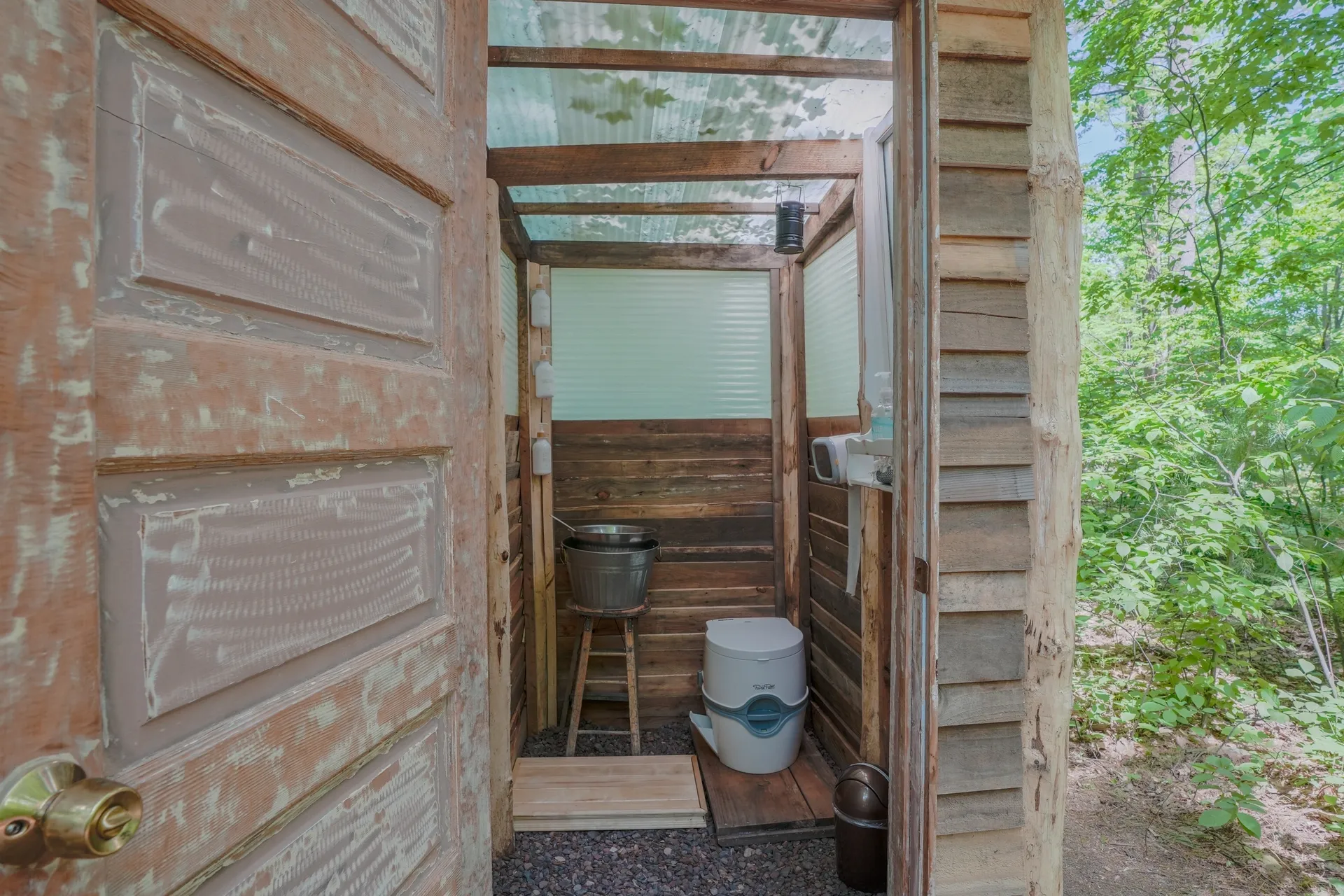 A wooden cabin with a toilet and bucket in it.