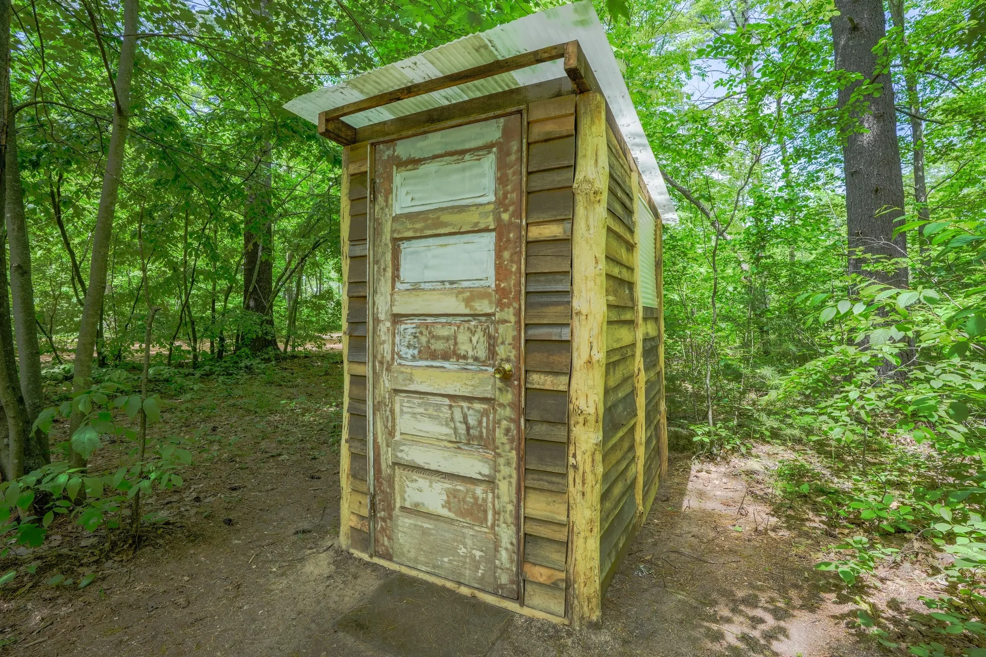 A outhouse in the middle of a forest.