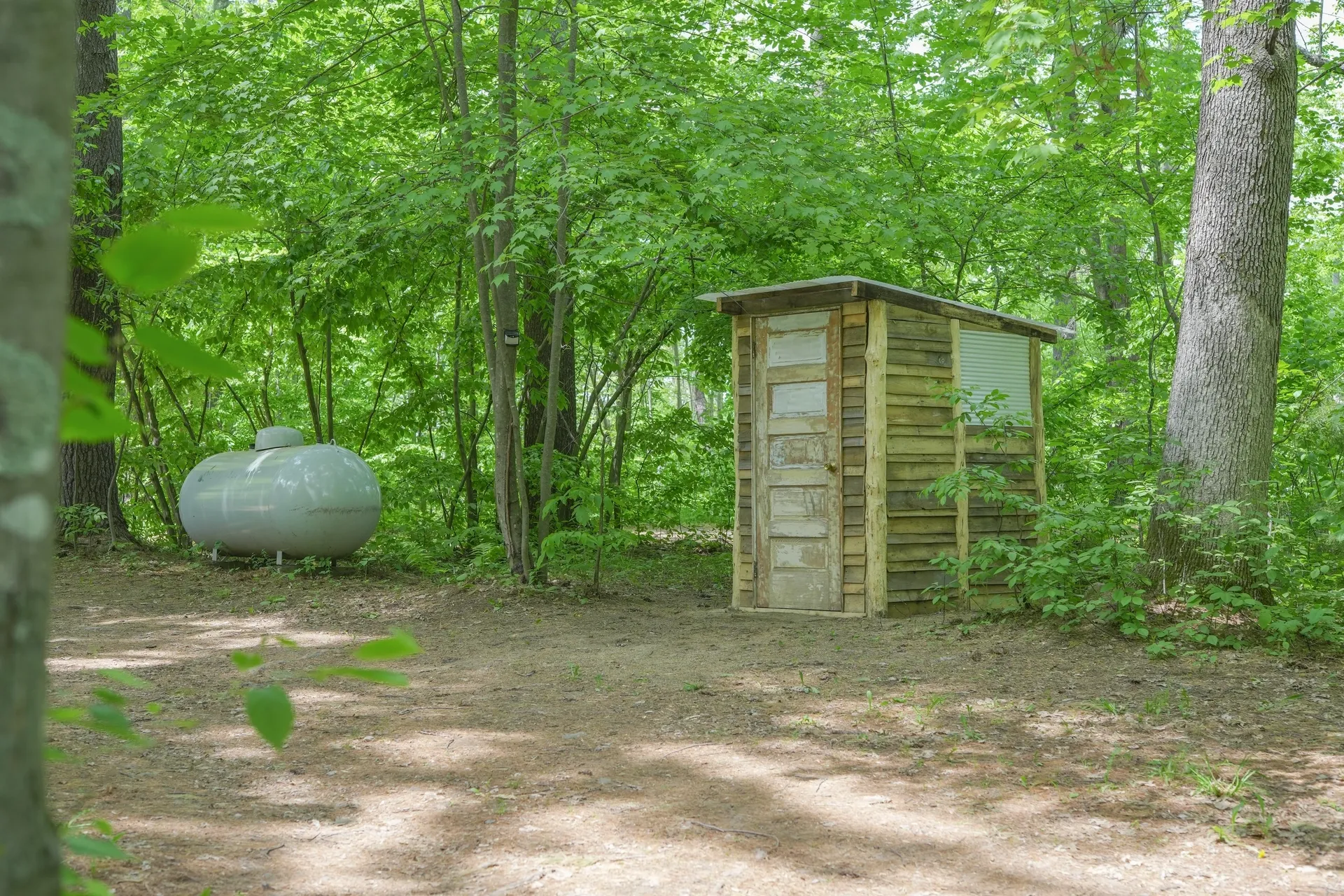 A outhouse in the middle of a forest.