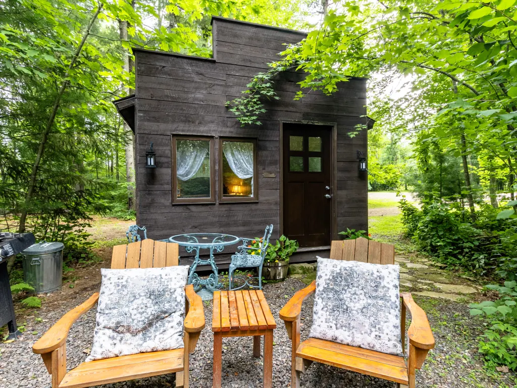 A couple of chairs and tables in front of a house.